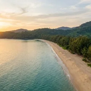 Empty golden-hour beach in Khao Lak Thailand with turquoise sea and jungle hills — things to do in Khao Lak Thailand